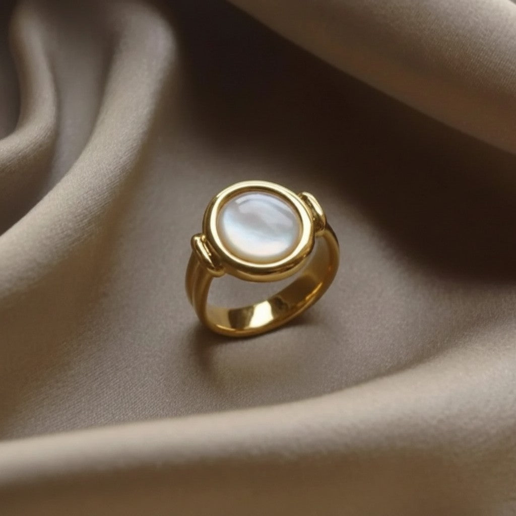 Anel elegante Arrabida Atelier em ouro com pedra redonda de madrepérola sobre tecido de seda bege